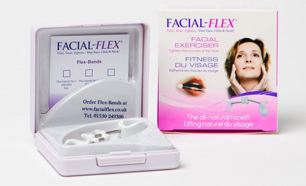 A Facial-Flex facial exerciser as presented in its hard carry case with a packet of additional flex bands sat beside the outer cardboard box packaging